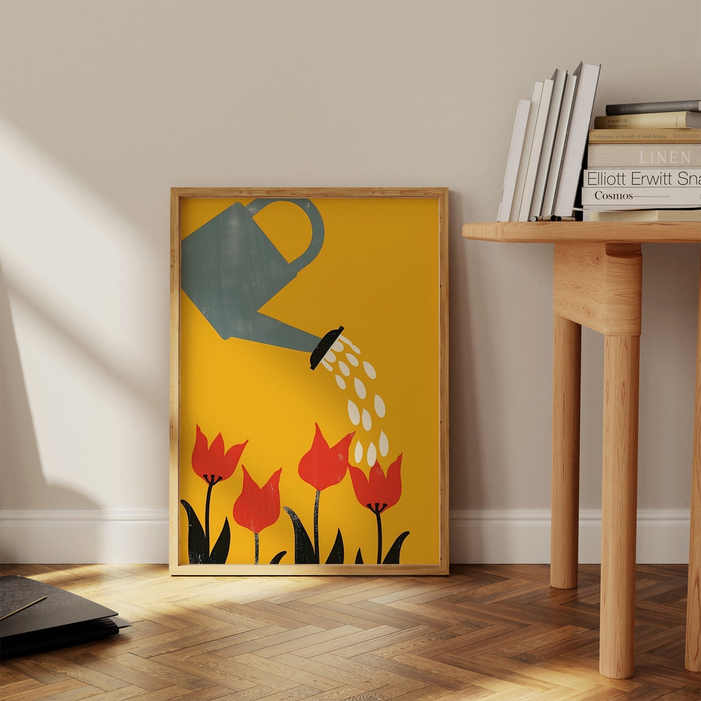 A framed poster of a watering can pouring water on red tulips against a yellow background, in a cozy room corner.