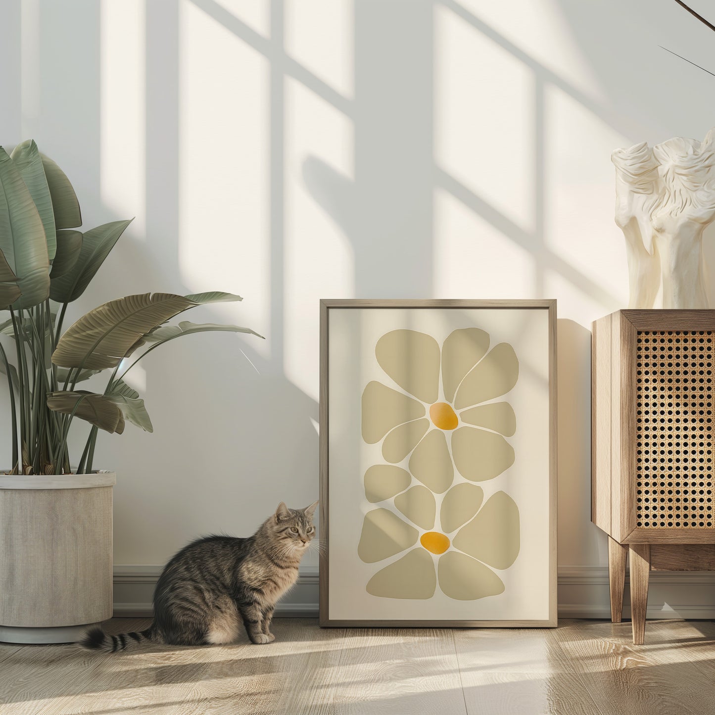 A cat next to a framed artwork with a floral design in a sunlit room.