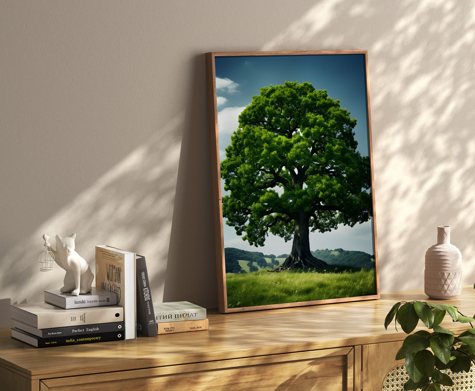 A framed picture of a tree leaning against a wall beside books and decorative items.