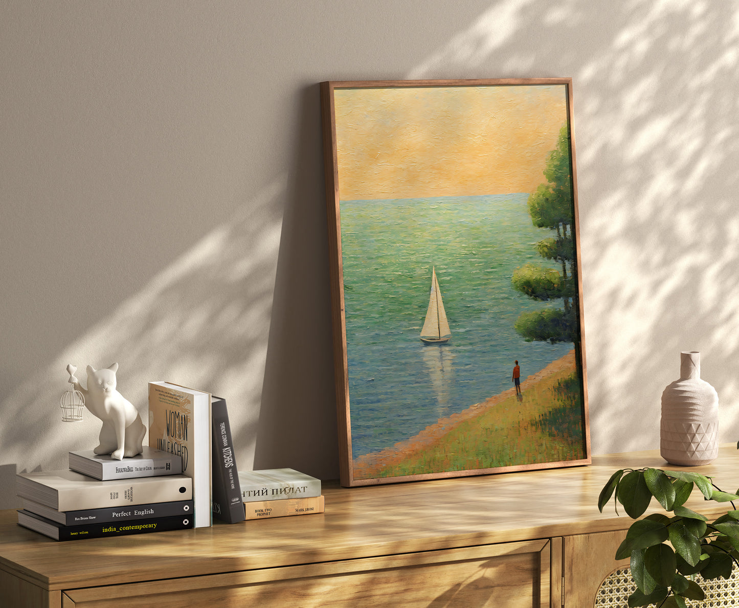 A tranquil painting of a sailboat on water beside books on a wooden cabinet in a sunlit room.
