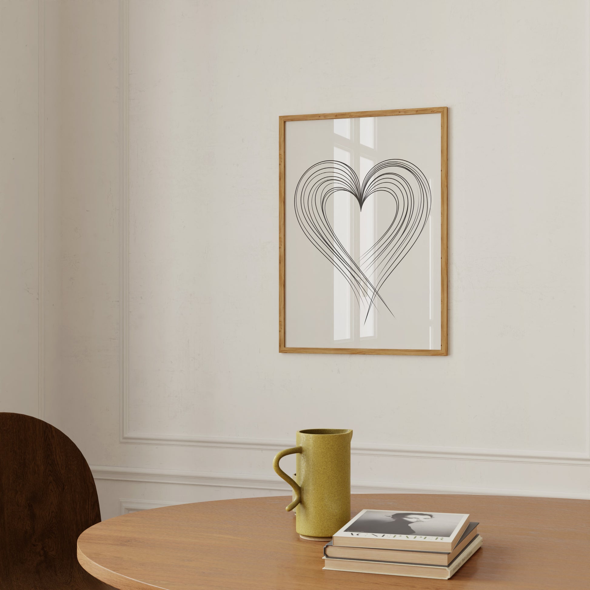 A framed heart illustration on a wall above a wooden table with a mug and books.