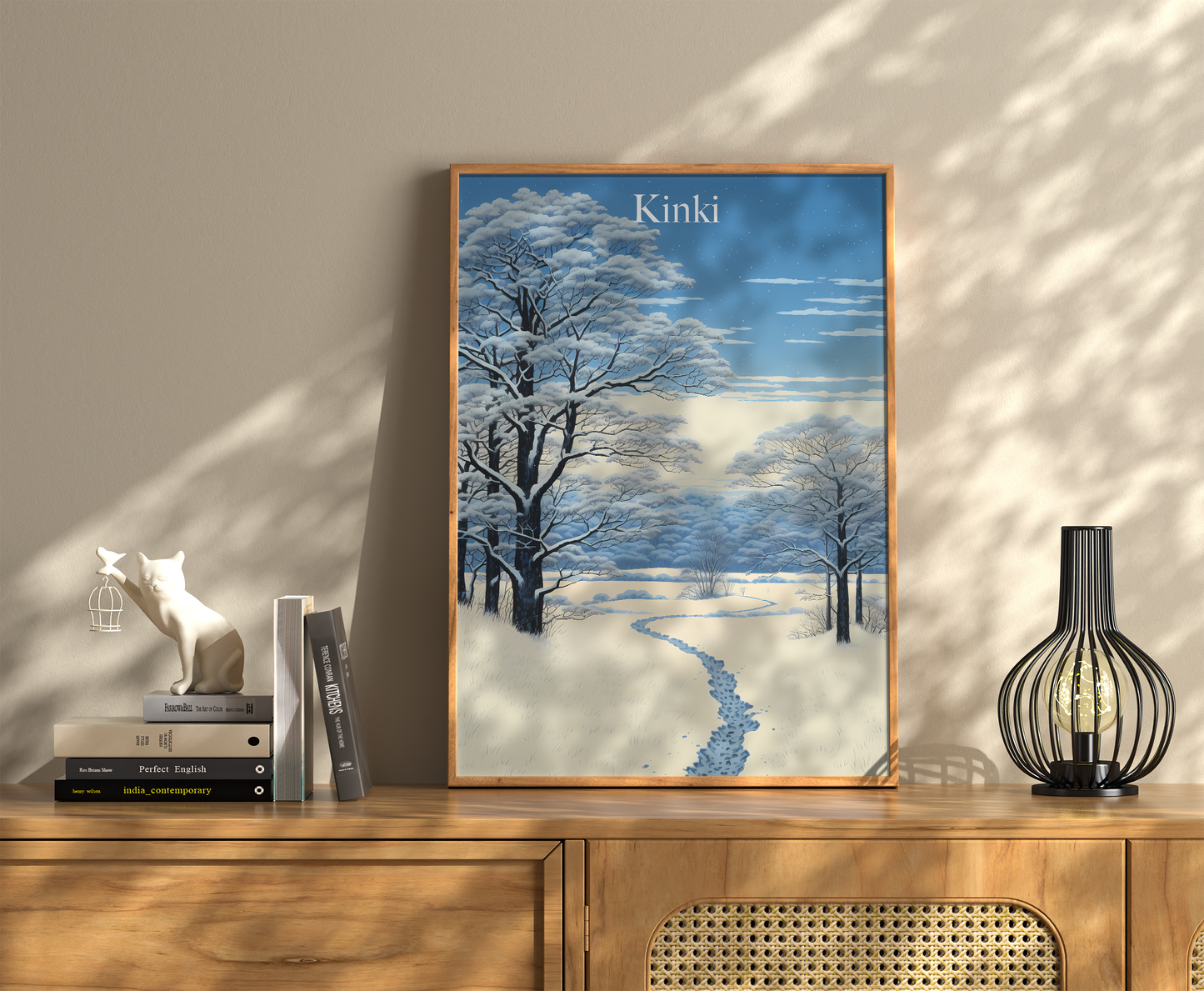 A framed winter landscape painting on a wall above a wooden cabinet with books and decorative items.