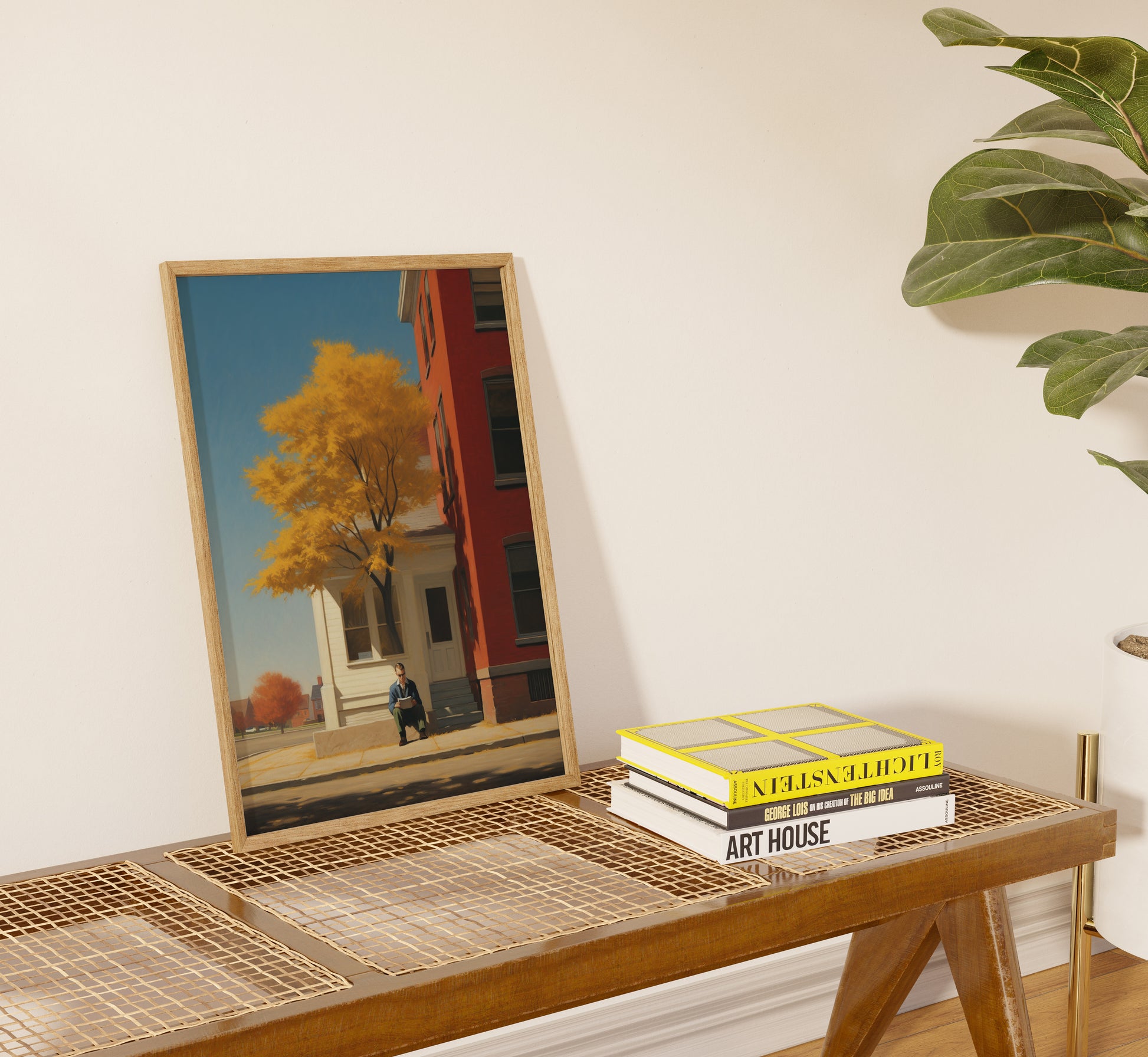 Framed painting on a console table beside books with a plant in the background.