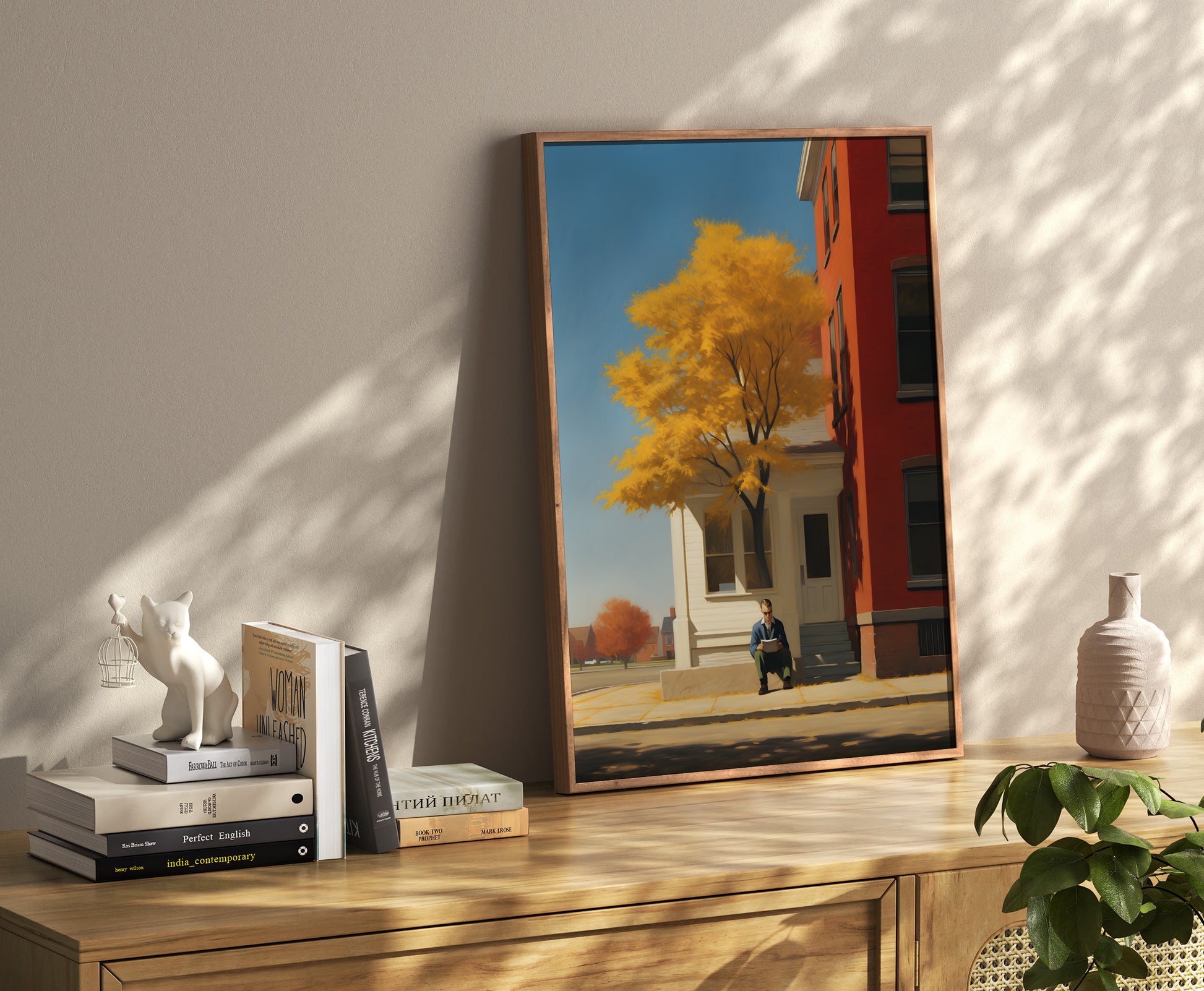 A framed painting leaning against a wall, depicting a person sitting by a tree with autumn leaves.