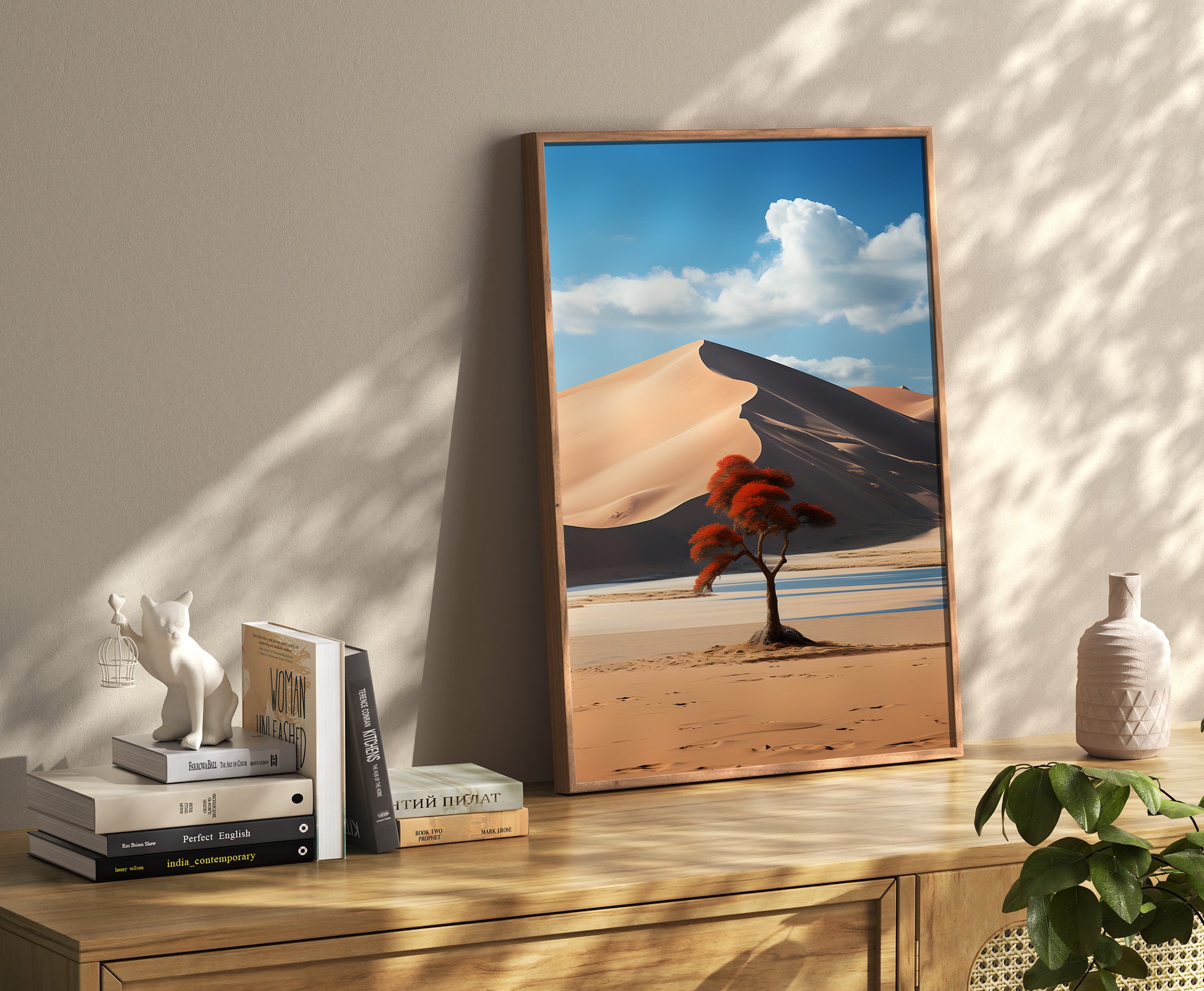 Framed desert landscape poster on a wooden floor leaning against a wall with decorative items.
