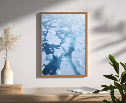 A framed picture of water reflections on a wall, beside a vase and books.