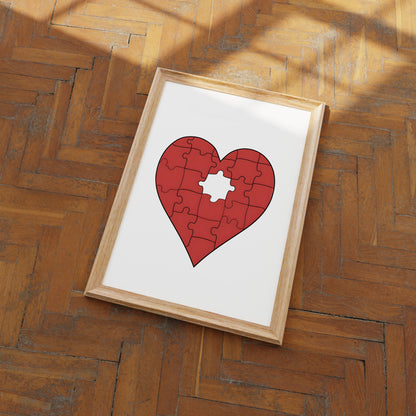 A framed puzzle in the shape of a heart with one piece missing, placed on a wooden floor.