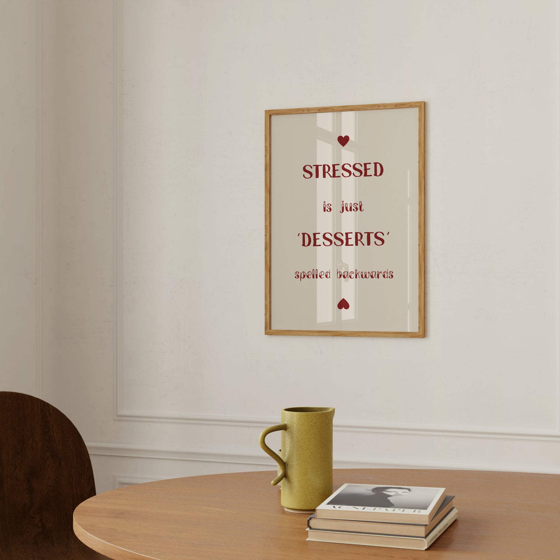 A framed quote on the wall that reads "stressed is just desserts spelled backwards," with a mug and book on a table.