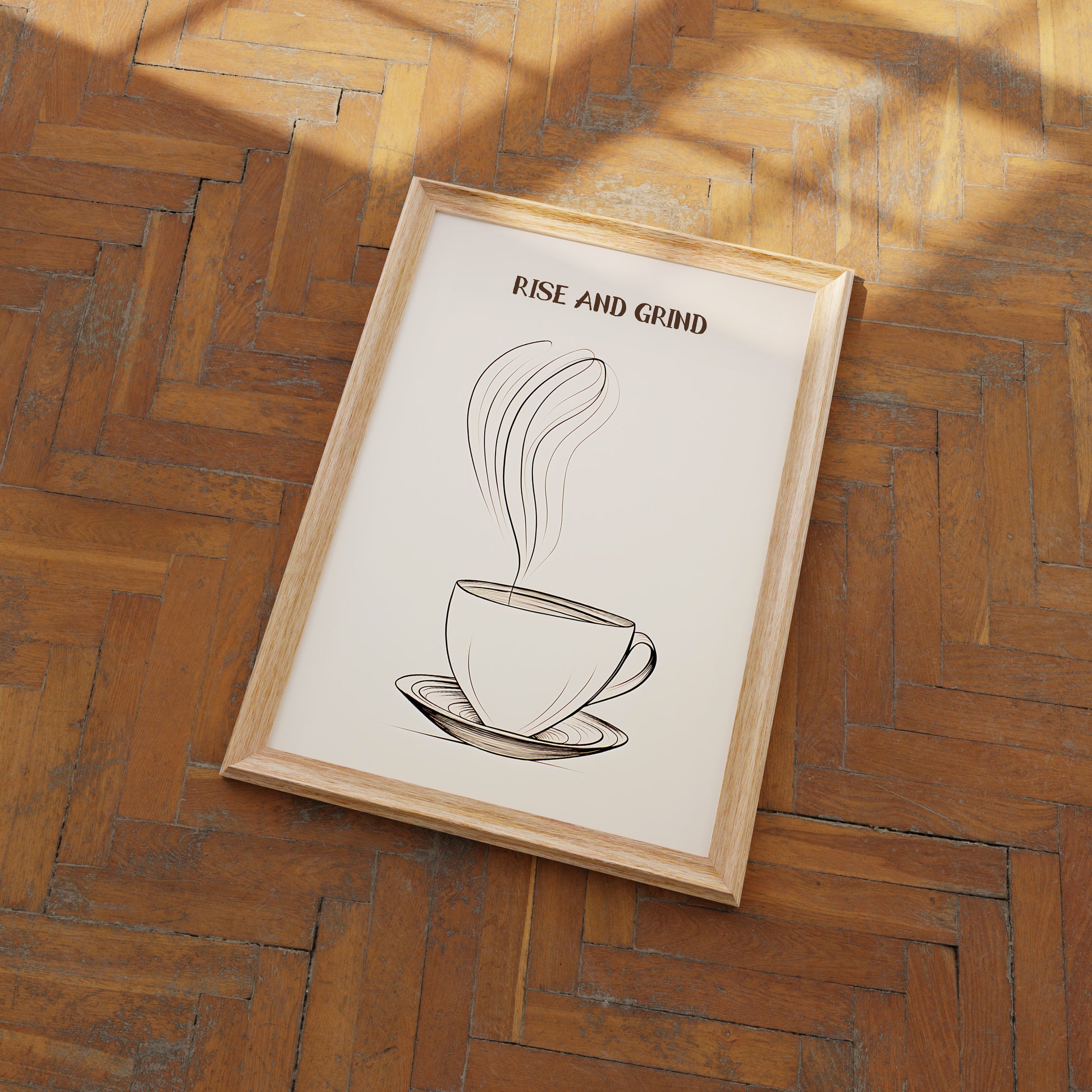A framed poster of a coffee cup with the phrase "RISE AND GRIND" on a wooden floor.