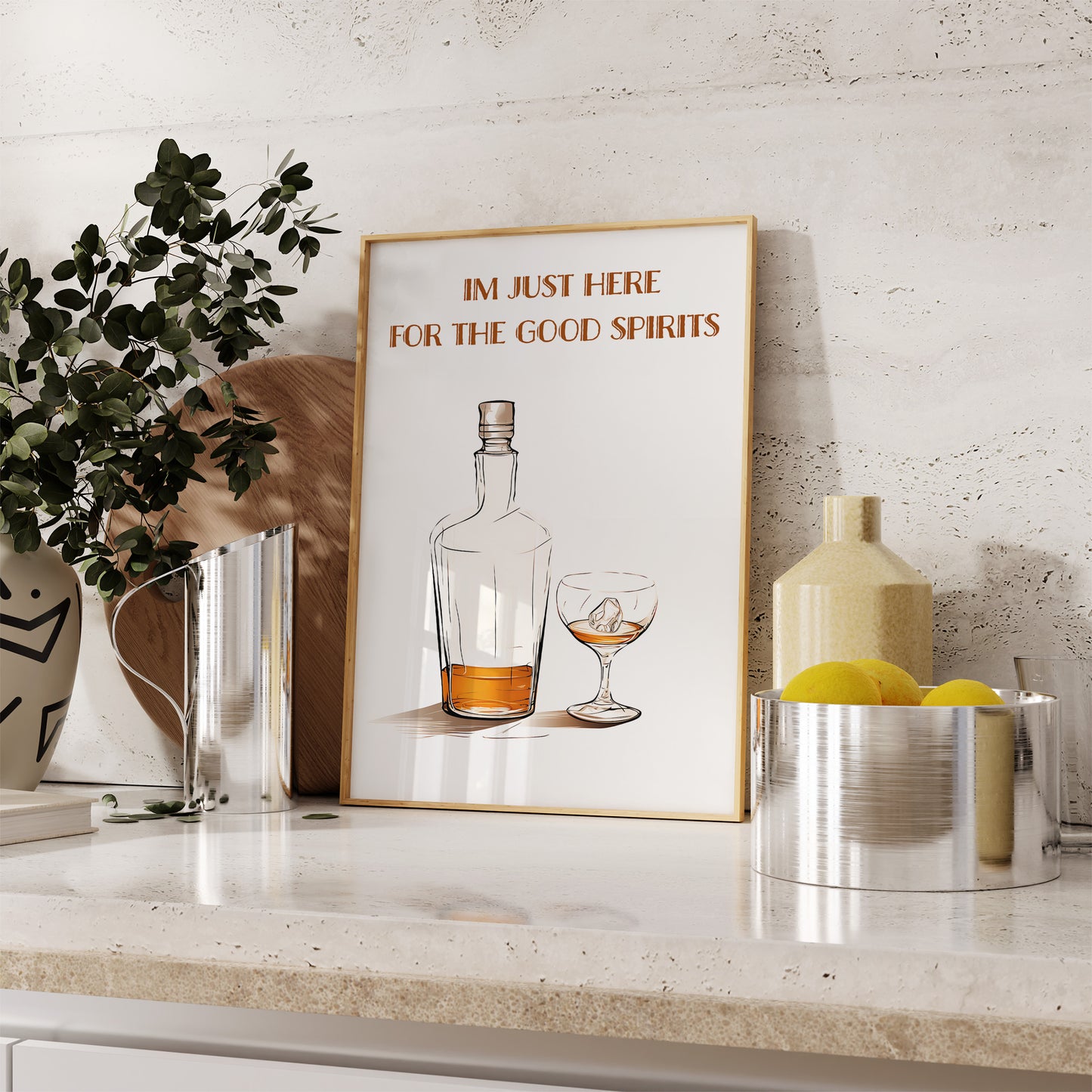 A framed quote on a kitchen countertop says "I'm just here for the good spirits" with a drawing of a liquor bottle and glass.