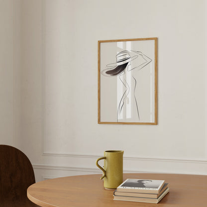 A framed abstract artwork of a figure on a wall above a table with a mug and books.