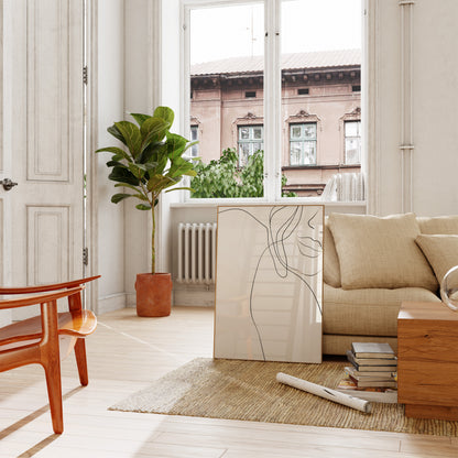 A cozy living room with a sofa, plant, and art leaning against the wall.